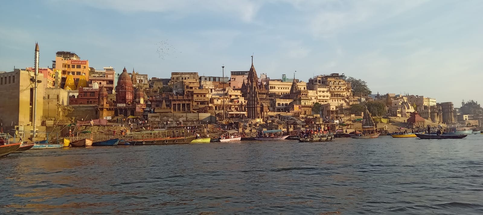 The ghats of Varanasi seen from the Ganga, with temples and boats along the riverbank