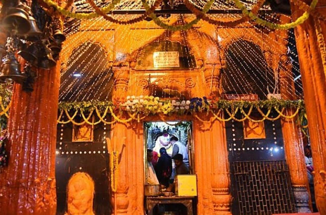 The saffron-painted inner shrine of Kal Bhairav Temple, hung with marigold garlands, bells and lights
